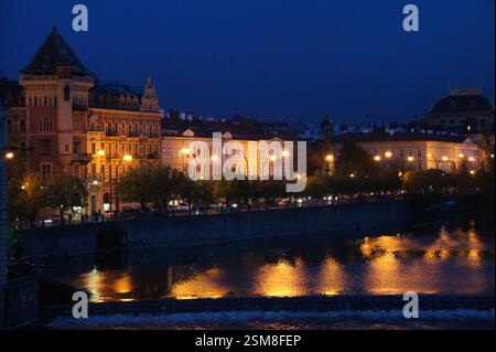 Le pont Charles, symbole de Prague, s'étend sur la rivière Vltava. Les bâtiments illuminés le long de la rive créent une atmosphère magique. Réf Banque D'Images