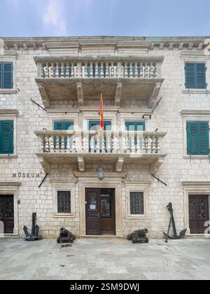 Kotor, Monténégro - 2 juillet 2024 : ancien centre historique. Façade du Musée maritime avec ancres et canons à l'avant. Drapeau national du Monténégro Banque D'Images