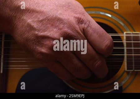 Photo d'une main sur le trou sonore d'une guitare pour amortir le son. Banque D'Images