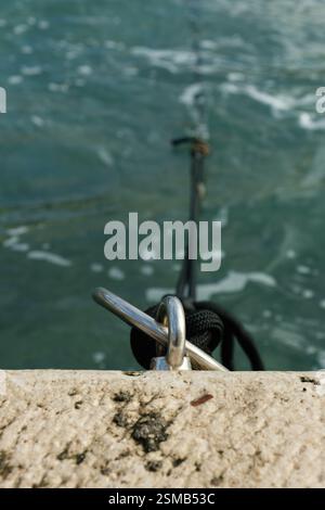 Anneau d'amarrage avec corde sur le bord de l'eau dans un port méditerranéen Banque D'Images