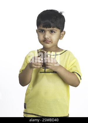 Les Indiens de l'Asie du Sud boy holding chocolat dans la main dans l'école maternelle M. Banque D'Images