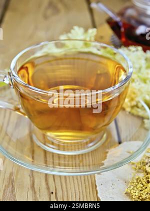 Meadowsucette thé d'une tasse en verre et théière, fleurs séchées sur papier Meadowsucette, fleurs fraîches de Meadowsucette sur une planche de bois Banque D'Images