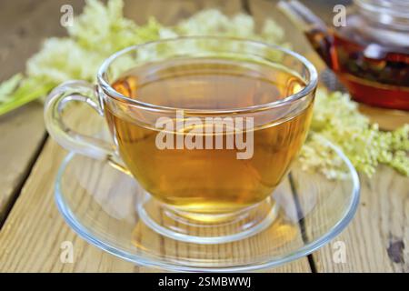 Meadowsweet thé d'une tasse en verre et théière, fleurs fraîches de Meadowsweet sur un backgroun de planches en bois Banque D'Images