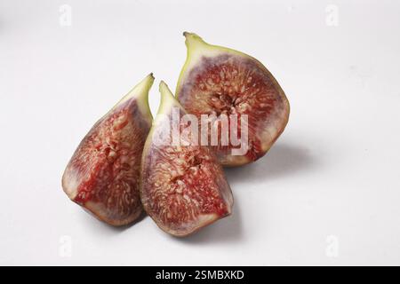 Fruit, Figs Ficus Carica Anjir coupé en trois morceaux texture juteuse rouge sur fond blanc Banque D'Images