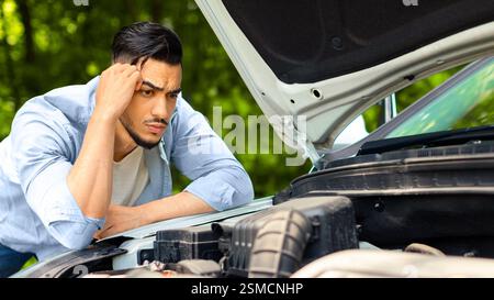 Perplexe, homme arabe pendu sur le capot de la voiture Banque D'Images