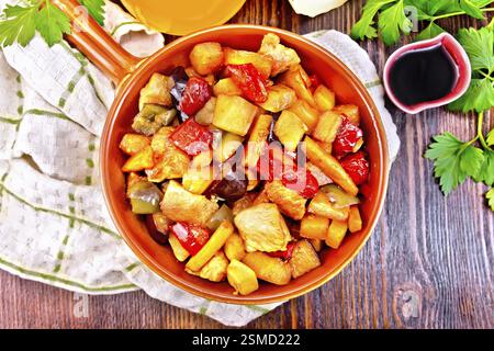Rôti de viande, courgettes, aubergines, carottes et poivrons doux avec miel, sauce soja et vin rouge dans une poêle sur une serviette sur le fond de th Banque D'Images