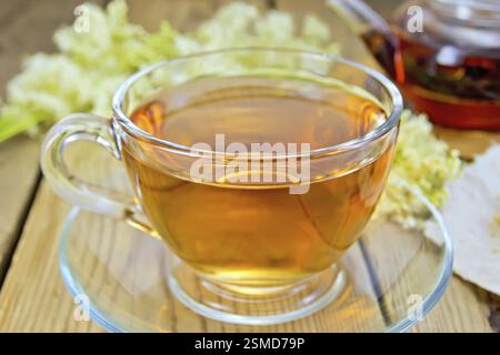 Meadowsweet thé d'une tasse en verre et théière, fleurs séchées sur papier MeadowSweet, fleurs fraîches Meadowsweet sur le fond de planches en bois Banque D'Images