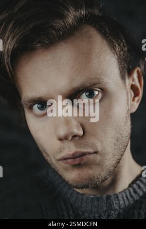 Portrait gros plan d'un homme aux yeux captivants sur fond sombre Banque D'Images