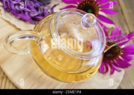 Tisane dans une théière en verre, fleurs fraîches et séchées d'échinacée sur un fond de planches en bois Banque D'Images