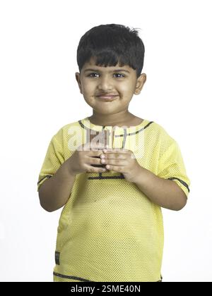Les Indiens de l'Asie du Sud boy holding chocolat en main l'école maternelle M. Banque D'Images
