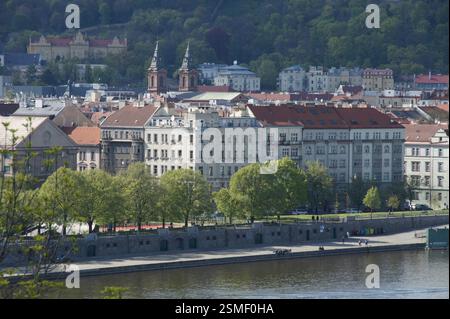 Paysage urbain. Des toits rouges bordent une rive, avec des arbres feuillus encadrant des bâtiments historiques et des églises. Une scène vibrante de la vie quotidienne dans une tête européenne Banque D'Images