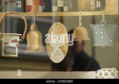 Figurine de chat en céramique suspendue sur une étagère avec des cloches et de la poterie. Chat heureux avec les bras croisés, disant 'Salut!'. 'Šéf' est tchèque pour 'Boss', indiquant un pla Banque D'Images