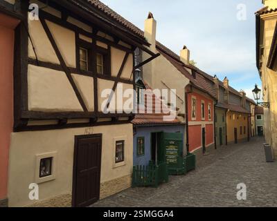Scène de rue à Prague, République tchèque. Des bâtiments colorés avec des toits de tuiles et des accents de bois bordent une ruelle pavée. Une petite porte avec un vert Banque D'Images