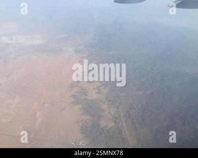 Une vue aérienne à couper le souffle se déploie : les montagnes enneigées traversent le ciel, leurs sommets déchiquetés contrastent fortement avec le vaste paysage désertique qui s'étend Banque D'Images