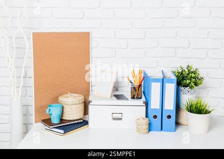 Espace de travail organisé avec des solutions de rangement, de la papeterie et des éléments décoratifs dans un cadre lumineux Banque D'Images