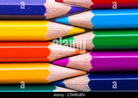 Arrangement coloré de crayons de couleur dans diverses nuances et teintes empilées soigneusement sur une surface plane Banque D'Images