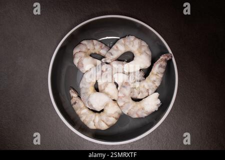 Crevettes tigrées crues congelées crevettes dans un bol gris sur une table de cuisine grise Banque D'Images