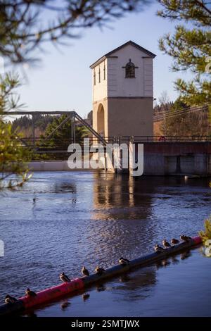 Rånåsfoss où la force de la nature rencontre l'ingéniosité humaine. La lumière dorée révèle la danse des tourbillons et de l’architecture, un équilibre entre puissance et harmoy Banque D'Images