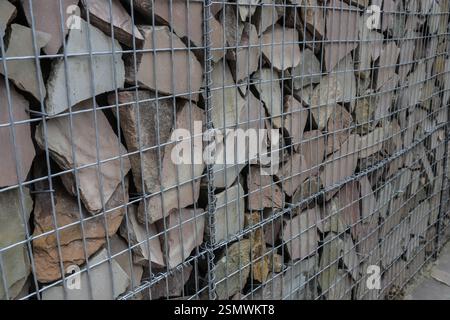 Des roches de différentes tailles sont soigneusement disposées et maintenues en place par un treillis métallique, formant une barrière robuste à un emplacement de construction. Banque D'Images