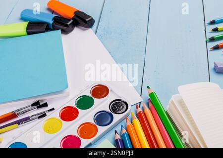 Fournitures d'art lumineuses et colorées disposées sur une table en bois bleu prête pour des projets créatifs dans un cadre cosy Banque D'Images