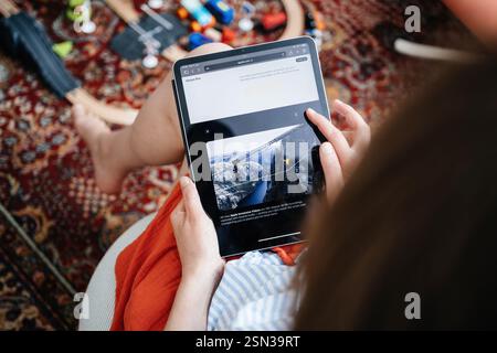 Paris, France - 11 juin 2023 : une personne parcourant le contenu Apple Vision Pro sur une tablette, visionnant des fonctionnalités vidéo immersives avec un paysage montagneux pittoresque Banque D'Images