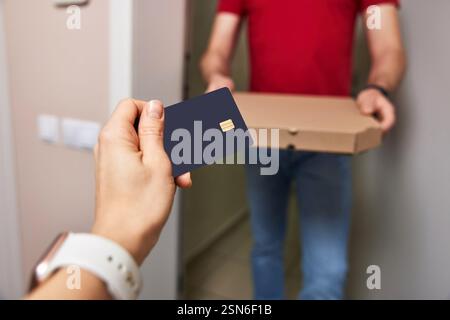 femme payant pour la pizza avec une carte de crédit noire à la porte, gros plan Banque D'Images