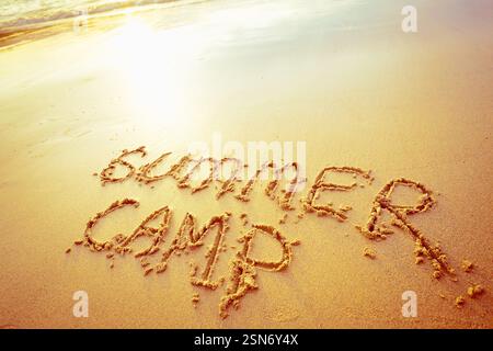 Camp d'été écrit dans le sable sur une plage pendant le coucher du soleil crée une atmosphère nostalgique pour les vacanciers Banque D'Images
