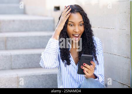 Une femme excitée réagissant joyeusement à Wonderful Good News sur son écran de smartphone Banque D'Images