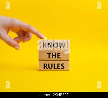 Connaître le symbole des règles. Les blocs de bois avec des mots connaissent les règles. Beau fond jaune. Main d'homme d'affaires. Affaires et connaître le concept de règles. Co Banque D'Images