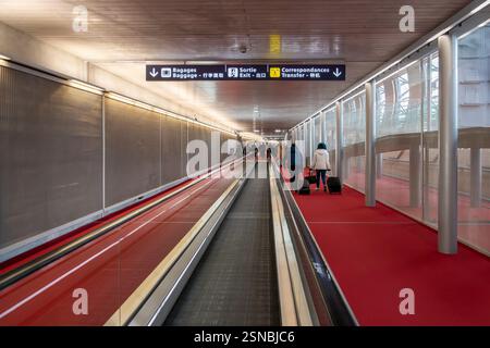 Vue d'une longue passerelle piétonne mobile avec un véhicule motorisé électrique ou des voyageurs à l'intérieur d'un terminal de l'aéroport Charles de Gaulle CDG à Paris France. Banque D'Images