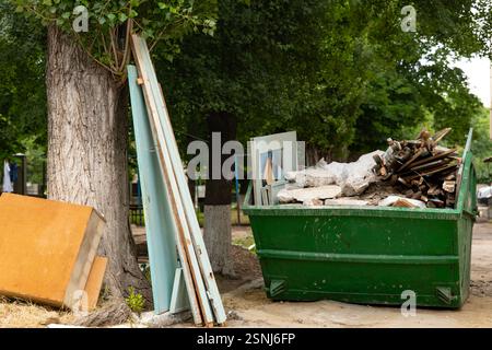 Conteneur de déchets industriels rempli de déchets de construction, situé dans la cour du bloc. Photo horizontale. Banque D'Images