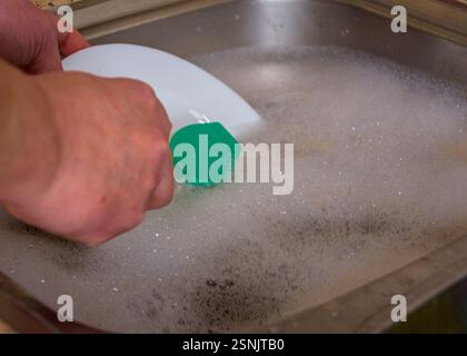 Laver la vaisselle à la main avec une éponge dans de l'eau savonneuse dans l'évier de cuisine Banque D'Images