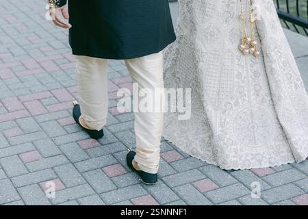 Un couple vêtu de vêtements traditionnels se promène sur un sentier à motifs, célébrant leur mariage avec joie. Banque D'Images