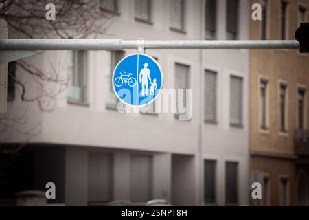 Un panneau bleu 'Gemeinsamer Geh und Radweg' (piste piétonne et cyclable partagée) est suspendu au-dessus d'une rue de la ville, guidant la circulation en toute sécurité pour les marcheurs A. Banque D'Images