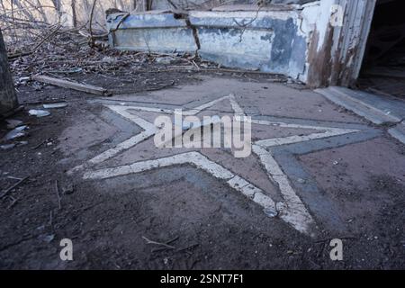 Une étoile rouge blanche et bleue fissurée sur le sol devant une façade de magasin abandonnée dans une ville fantôme Banque D'Images