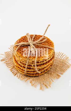Une pile de gaufres au caramel fraîchement préparées est présentée, attachées avec de la ficelle sur un tapis rustique en toile de jute. Les friandises dorées sont prêtes à ravir pendant le c national Banque D'Images