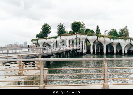 Les visiteurs se promènent le long d'une passerelle surélevée dans un parc riverain distinctif de New York. Banque D'Images