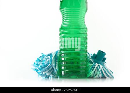 Bouteille en plastique avec désinfectant vert pour planchers et balai à franges avec fibres bleues et blanches sur une base propre, blanche et réfléchissante et un bac isolé blanc Banque D'Images