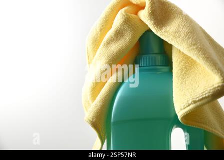 Détail du dessus d'une bouteille verte avec un produit nettoyant désinfectant et un chiffon en microfibre jaune sur le dessus avec un fond blanc isolé. Vue de face. Banque D'Images