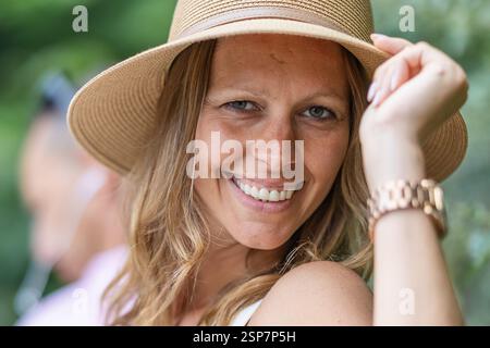 Gros plan d'une femme souriante portant un chapeau de paille élégant à l'extérieur Banque D'Images
