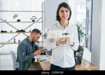 Femme debout devant l'homme qui est assis près de la table. Deux designers travaillant ensemble au bureau. Banque D'Images