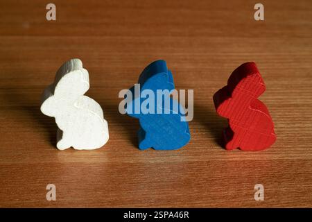 Trois figures de lapin colorées en bois l'une après l'autre sur une table en bois gros plan Banque D'Images