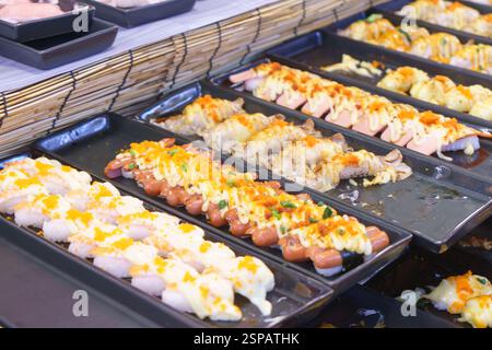 gros plan de diverses variétés de sushis exposées dans un stand de restauration de rue, avec salade d'algues, poulpe, crustacés, œufs de saumon, et anguille grillée. Banque D'Images