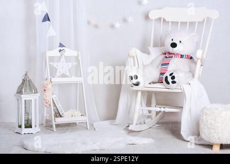 Chambre d'enfant confortable et lumineuse avec fauteuil à bascule et ours en peluche géant Banque D'Images
