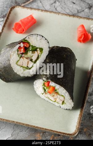 Sushi burrito avec riz, poulet, légumes et laitue gros plan dans une assiette sur la table. Vertical Banque D'Images