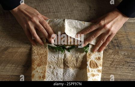 Envelopper le shawarma dans du lavash avec du poulet et des légumes. Banque D'Images