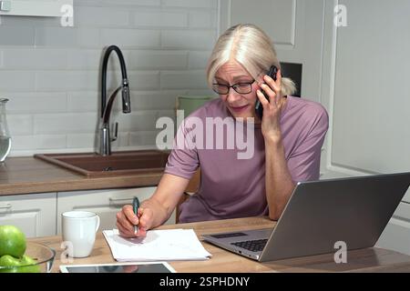 Travail à distance : une femme mature combine appels et rendez-vous Banque D'Images