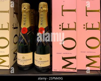 Gros plan de deux bouteilles de champagne Moët & Chandon Imperial brut positionnées devant deux boîtes roses Rosé Impérial. Les bouteilles et les boîtes comportent gol Banque D'Images