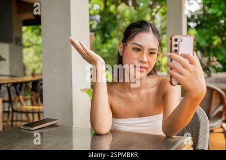 Young woman using mobile phone in cafe Banque D'Images