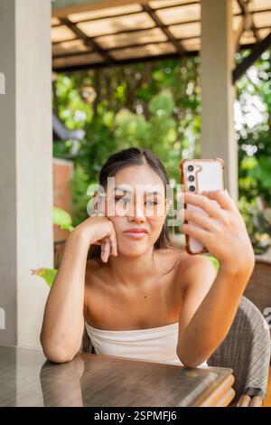 Young woman using mobile phone in cafe Banque D'Images
